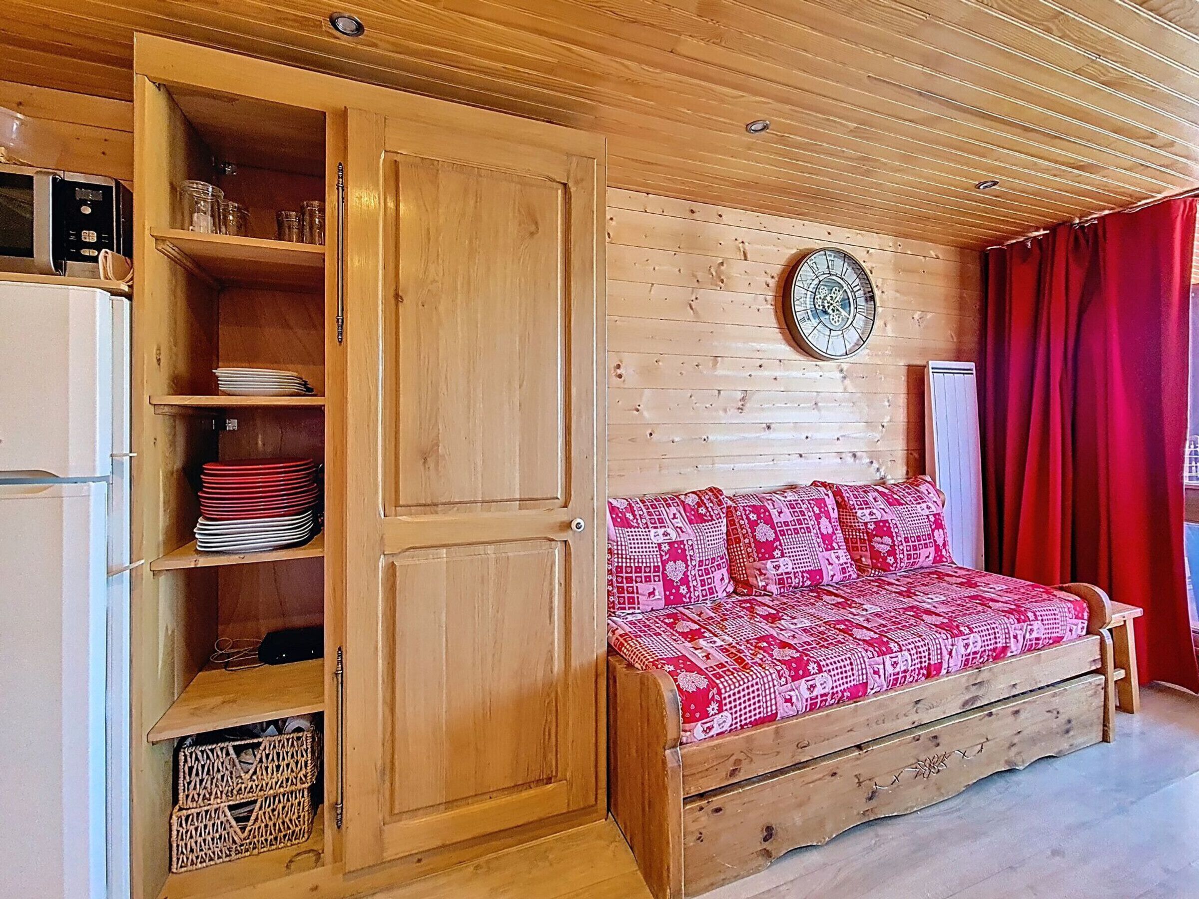 Een gezellige kamer met een houten garderobe, een bed met beddengoed met een patroon, en een wandklok.