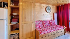 Una habitación acogedora con un armario de madera, una cama con ropa de cama estampada y un reloj de pared.