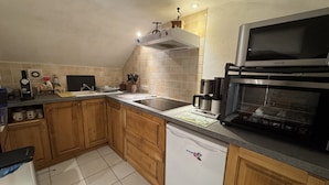 Une cuisine avec des meubles de rangement en bois, un lave-vaisselle, une machine à café et un four à micro-ondes.