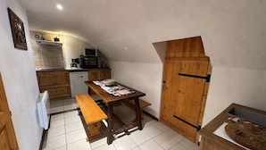 Une cuisine de taille réduite avec une table en bois, un banc et un meuble en bois doté d’une porte coulissante.