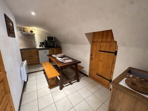 Eine kompakte Küche mit einem Holztisch, einer Bank und einem Holzschrank mit Schiebetür.