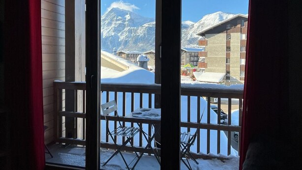 Een balkon met uitzicht op een met sneeuw bedekte berg en gebouwen.