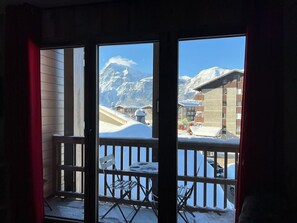 Ein Balkon mit Blick auf einen schneebedeckten Berg und Gebäude.