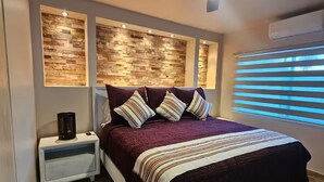 A bedroom with a bed, nightstands, a ceiling fan, and a wall-mounted air conditioner. - Flor del Desierto - Lovely house with cool AC in vibrant LORETO, BCS (BCS)