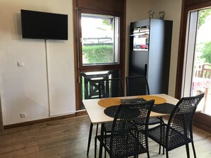 A dining area with a table, chairs, a TV mounted on the wall, and a refrigerator. - 2-room apartment at cable car base, pets allowed, parking (Arâches-la-Frasse)