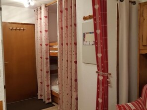 A room with a wooden door, a bunk bed, and a red-striped sofa. - Cozy Studio with terrace, 4 people, private parking (Arâches-la-Frasse)