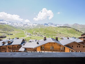 Eine Berghütte mit Holzgebäuden, einer Skipiste und schneebedeckten Bergen im Hintergrund.