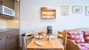 Une cuisine compacte équipée d’un four à micro-ondes, d’une machine à café et d’une table à manger en bois avec des chaises.