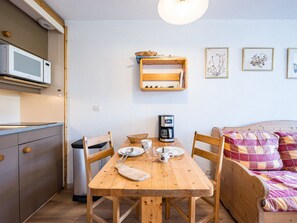 A compact kitchen with a microwave, a coffee maker, and a wooden dining table with chairs. - Bright central studio, south balcony, 4 people (Val Thorens)
