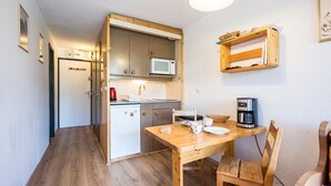 Une cuisine compacte équipée d’un four à micro-ondes, d’une machine à café et d’une table à manger avec des chaises.