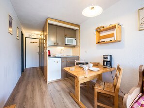 A compact kitchen with a microwave, coffee maker, and a dining table with chairs. - Bright central studio, south balcony, 4 people (Val Thorens)