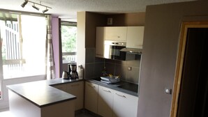 Eine kompakte Küche mit einer zentralen Kochinsel, einem eingebauten Backofen und einer Mikrowelle.