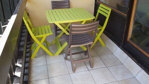 Ein kleiner Außenbereich mit Tisch und zwei Stühlen.