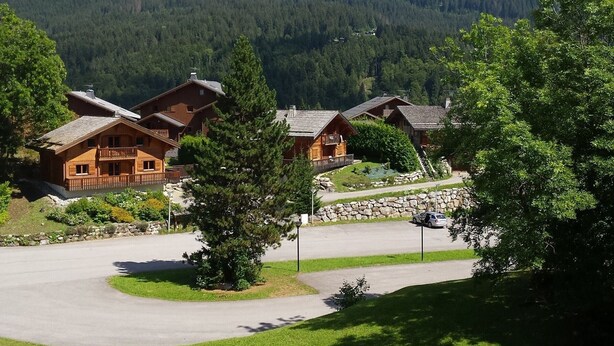 Eine Lodge mit mehreren Holzhütten, einer Steinmauer und einer Auffahrt zu einem Parkplatz.