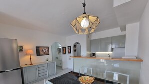 A modern kitchen with a central island, a dining table with chairs, and a hanging light fixture. - Comfortable apartment with terrace, central, near the beach (L'Escala)