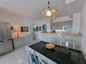 Uma cozinha moderna com uma ilha central, uma mesa de jantar com cadeiras e um lustre.