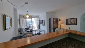 A modern kitchen with a wooden countertop, a refrigerator, and a dining area with a table and chairs. - Comfortable apartment with terrace, central, near the beach (L'Escala)