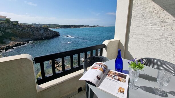A balcony with a view of the sea, a table with a magazine, a blue bottle, and two glasses. - Comfortable apartment with terrace, central, near the beach (L'Escala)