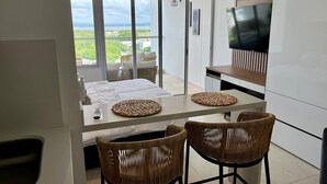 Una moderna camera d'albergo con balcone, un letto, una TV e poltrone in vimini.