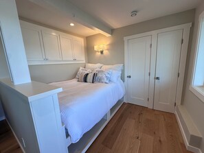 A bedroom with a bed, white cabinets, a bedside table, and a door. - Comfy Studio in Charming Downtown Sausalito (Sausalito)