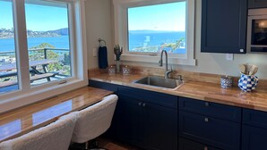 Cocina con vista al mar, encimeras de madera y armarios azul oscuro.