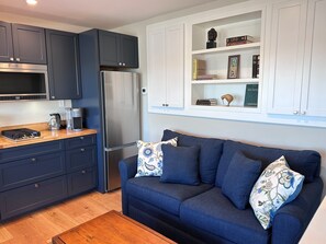 A modern kitchen with dark cabinets, a stainless steel refrigerator, and a coffee maker on the counter. - Comfy Studio in Charming Downtown Sausalito (Sausalito)