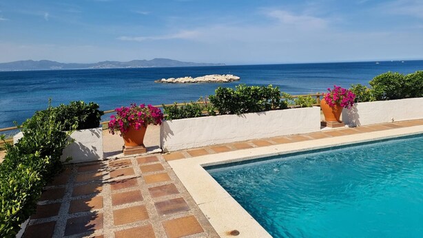 Ein Pool mit Blick auf das Meer und die dahinter liegenden Berge.