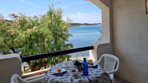 Ein Balkon mit Tisch für Zwei, mit Blick auf Wasser und Grün.