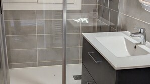 Un baño con lavamanos blanco, mueble oscuro y paredes con azulejos.