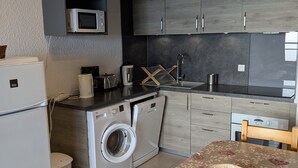 Cocina compacta con lavadora, microondas y pileta.