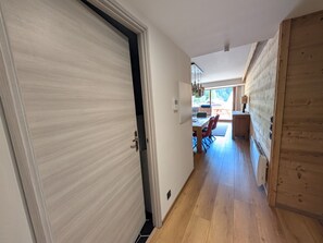 Ein Flur, der zu einem Essbereich mit Tisch und Stühlen führt, mit Holzboden und Blick ins Freie.