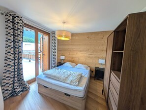 A bedroom with a bed, bedside tables, a wardrobe, and a view of the outdoors. - Stunning new apartment 8 pers, 55m² south terrace, near slopes (Montgenèvre)