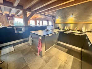 A kitchen with a central island, stainless steel appliances, and a view of the outdoors. - Luxury Chalet 5 Bedrooms with Jacuzzi and Parking (Arâches-la-Frasse)
