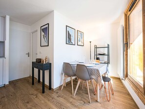Ein Essbereich mit einem Tisch für vier Personen, einem kleinen Beistelltisch und einem Regal mit Geschirr.