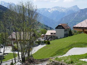 Ett bostadsområde med hus, en gräsklädd kulle och berg i bakgrunden.