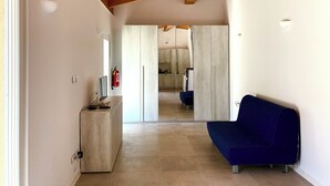 Ein modernes Interieur mit Holzboden, einem blauen Sofa, einem Holzkasten und einer Küche im Hintergrund.