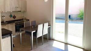 Eine moderne Küche mit Essbereich, ausgestattet mit einem großen Fenster und einer Schiebetür zum Außenbereich.