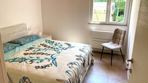 Ein Schlafzimmer mit einem Bett, einem Sessel, einem Fenster und einer Klimaanlage.
