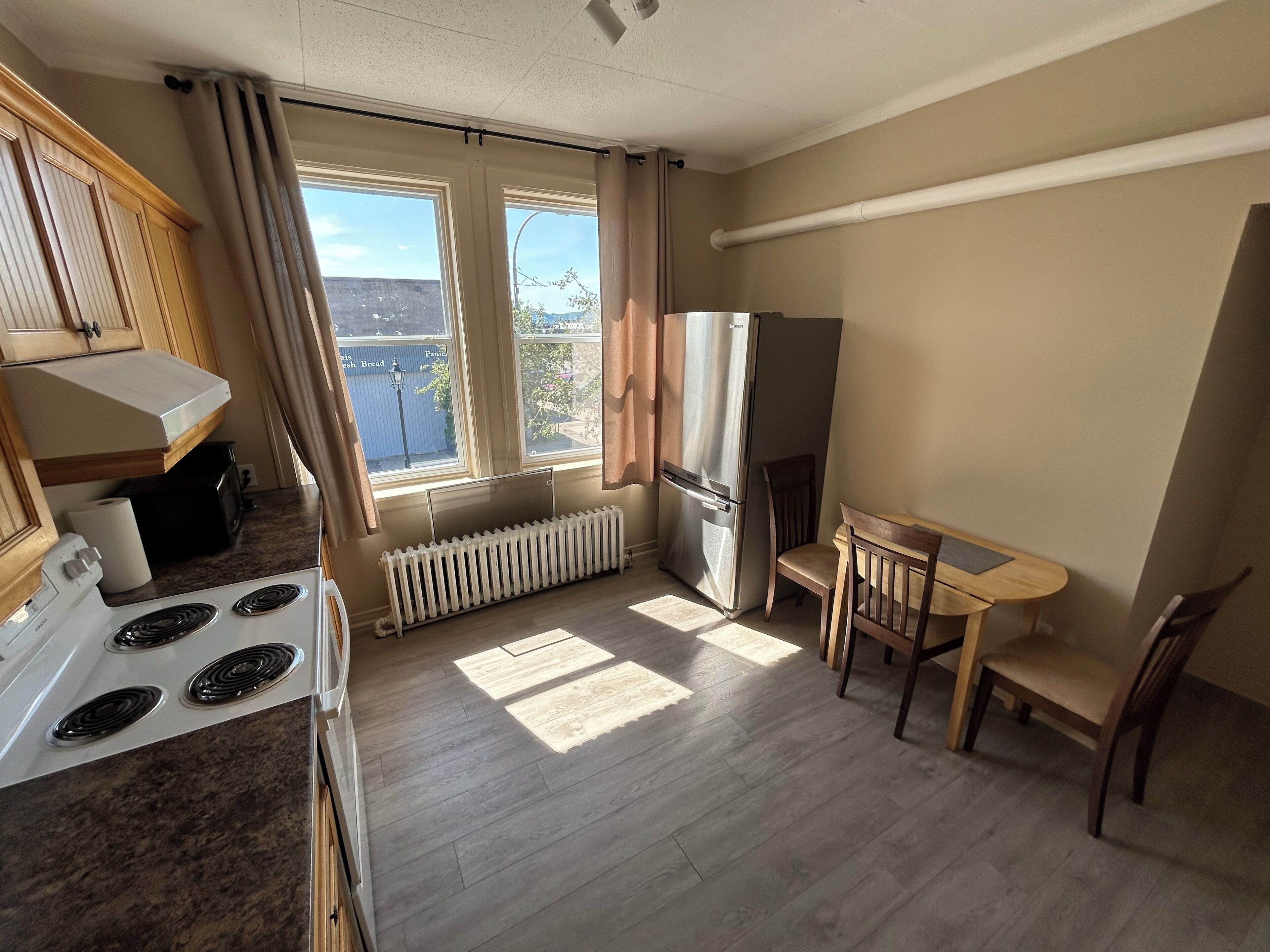 A compact kitchen with a stove, refrigerator, and a dining table with chairs.