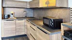 Cozinha moderna com armários de madeira, micro-ondas embutido e máquina de café.