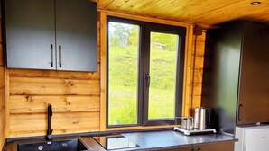 Een moderne keuken met houten plafond en wanden, een groot raam en roestvrijstalen apparatuur.
