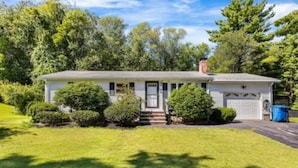 Ein Bungalow mit Veranda, Garage und gepflegtem Rasen.