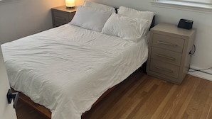 Ein Schlafzimmer mit Bett, Nachttisch, Lampe und Kommode.