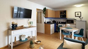 A compact living space with a kitchenette, a dining area, a sofa, and a TV mounted on the wall. - Studio ski-in/ski-out with large balcony at Les Orres (Les Orres)