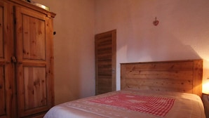 Ein Schlafzimmer mit einem hölzernen Kopfende, einem Bett mit einer beige farbenen Steudecke und einem Holzschrank.