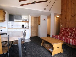 A compact kitchen with a dining area, a wooden bench, and a red patterned sofa. - 3-room apartment for 6, 200m from slopes - L'Alpe d'Huez (Huez)