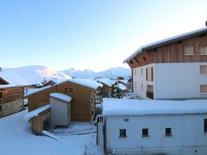 A snow-covered building with a wooden facade and a white upper section, set against a backdrop of snow-capped mountains. - 3-room apartment for 6, 200m from slopes - L'Alpe d'Huez (Huez)