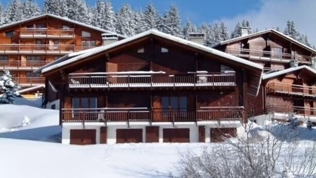 A wooden lodge with multiple balconies and a snow-covered landscape.