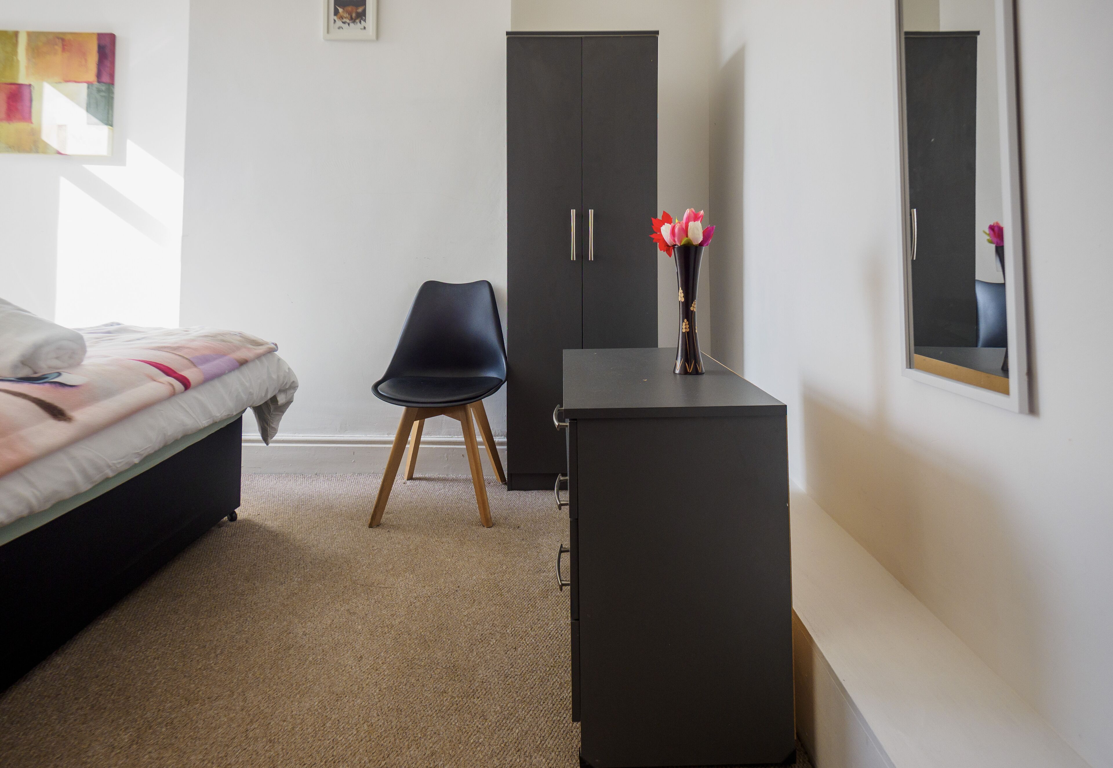 A bedroom with a bed, a desk, a chair, and a wardrobe.