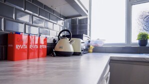 A kitchen with a kettle, a coffee machine, and a potted plant.